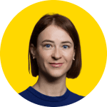 A woman with straight auburn hair and blue eyes, wearing a blue top, is shown against a bright yellow circular background, representing an EUD Board member.